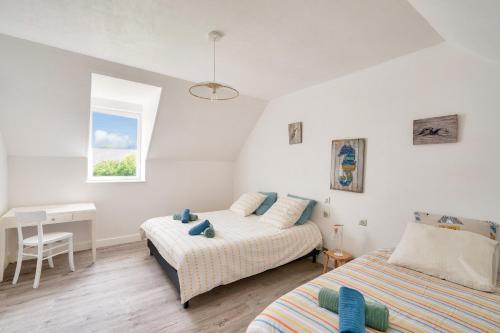 une chambre avec deux lits et un bureau et une fenêtre dans l'établissement Belle maison pour 7 à 300m de la plage au Guilvinec, au Guilvinec