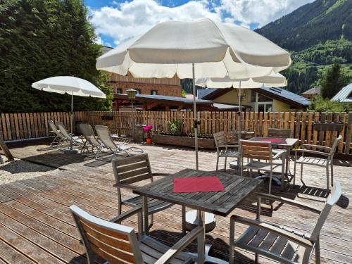 a wooden deck with tables and chairs with umbrellas at Alpenpension Gastein in Bad Gastein