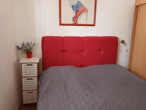 a bed with a red headboard in a bedroom at Apartman Karla in Makarska