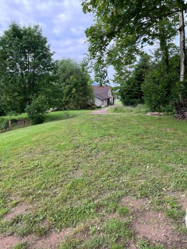 a field of grass with a house in the background at La barrique in Faymont