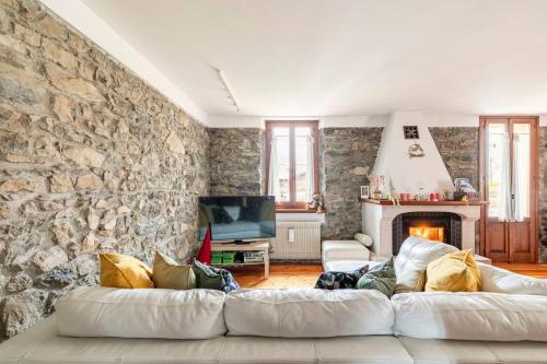a living room with a white couch and a stone wall at The Family Stone House Holidays Apartaments Dolomiti Cortina in Venas