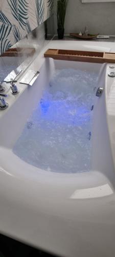 une baignoire remplie d'eau bleue dans une salle de bain dans l'établissement Bel appartement avec Balnéo, à Sainte-Marie-aux-Mines