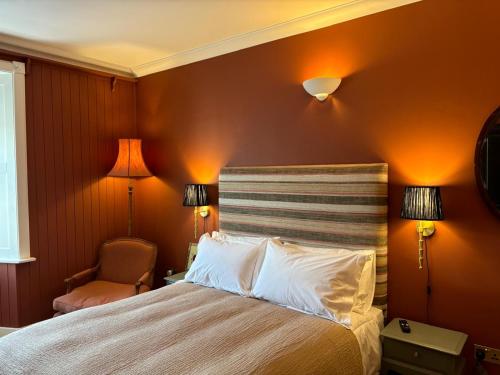 a bedroom with a bed with orange walls and two lamps at Hootananny in Inverness