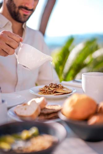 Un hombre está vertiendo leche en un plato de comida. en Eden Rose Grand Hotel BW Premier Collection, en Bormes-les-Mimosas
