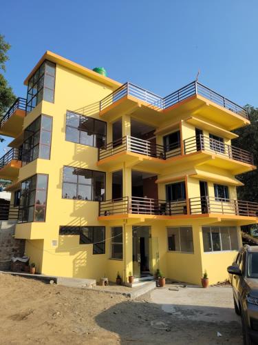 a yellow apartment building with a car parked in front at 11 Gaon Homestay Lansdowne in Lansdowne