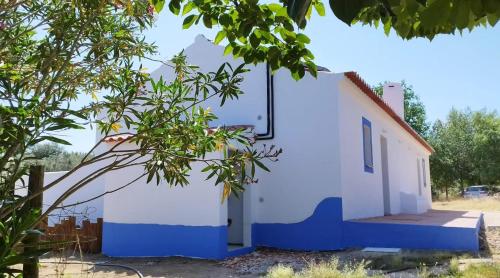 een wit en blauw gebouw met een boom bij Casa da Bolota T1 in Évora