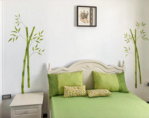 a bedroom with a green bed with two pillows at 2 bedrooms apartement at Mahebourg 300 m away from the beach with sea view furnished garden and wifi in Mahébourg