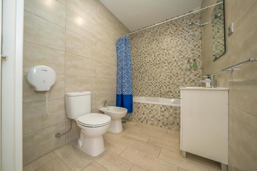 a bathroom with a toilet and a sink and a tub at Hostel Supremo in Armação de Pêra