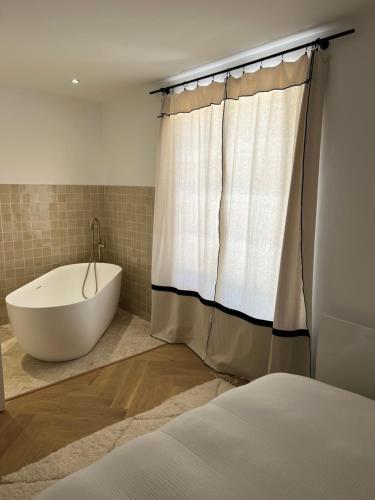 La salle de bains est pourvue d'une baignoire et d'un rideau de douche. dans l'établissement Villa Garonne, à Quinsac