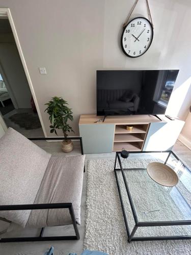 a living room with a tv and a clock on the wall at DK House in Colchester