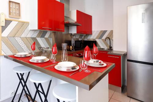 une cuisine avec des placards rouges et une table avec des verres à vin dans l'établissement Le Scarlett Nîmois, à Nîmes