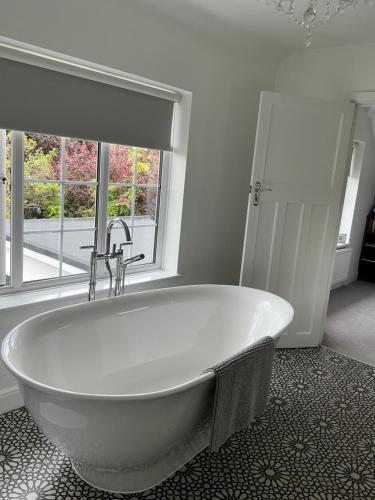a white bath tub in a bathroom with a window at Frinton45 in Frinton-on-Sea