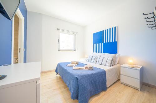 a white bedroom with a bed with a blue blanket at Hostel Supremo in Armação de Pêra