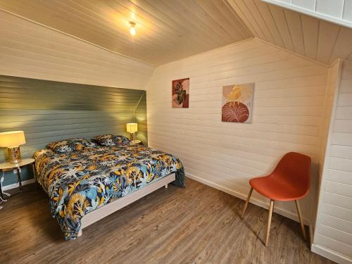 a bedroom with a bed and a red chair at T2 Ctre ville Fibre Literie Emma in Montrichard