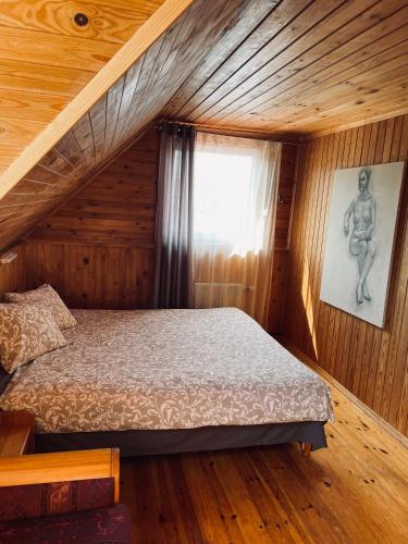 a bedroom with a bed in a wooden house at Viesu nams RŪĶĪŠI in Rugāji