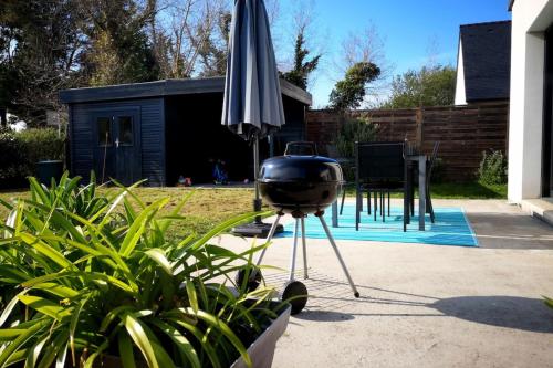 - un barbecue et un parasol à côté d'une maison dans l'établissement Côté surf maison ensoleillée à 150m de la plage, à Penmarcʼh