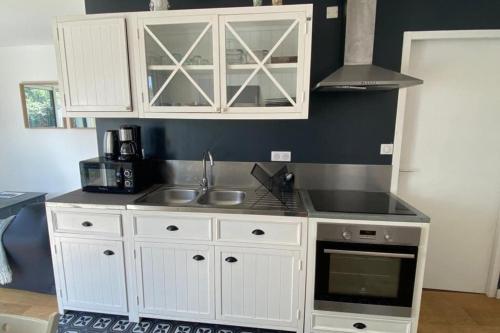 une cuisine avec des armoires blanches et un évier dans l'établissement Côté surf maison ensoleillée à 150m de la plage, à Penmarcʼh