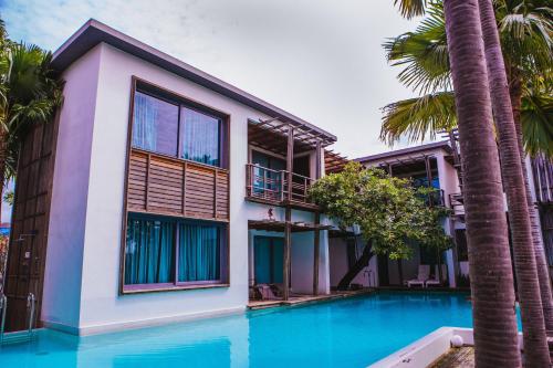 a villa with a swimming pool and palm trees at Paragon Inn in Lat Krabang