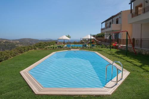 a swimming pool in the yard of a house with a playground at Triopetra Luxury Villas Fournou Lago in Triopetra