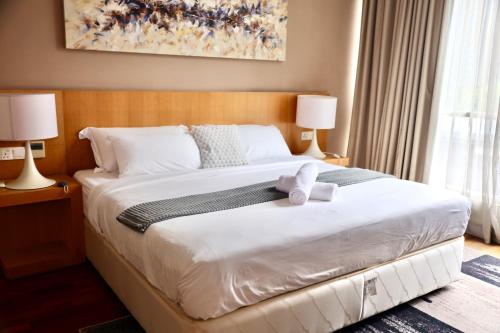 une chambre avec un grand lit blanc avec deux lampes dans l'établissement Home by Bella, à Kuala Lumpur