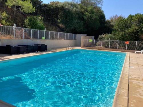 une piscine avec de l'eau bleue dans une cour dans l'établissement Studio Marcu vue mer, à Porticcio