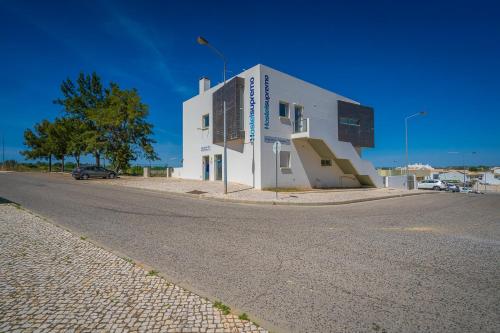 a white building on the side of a street at Hostel Supremo in Armação de Pêra
