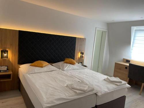 a bedroom with a large white bed with a black headboard at Hotel & Restaurant Bella Italia in Niederfell