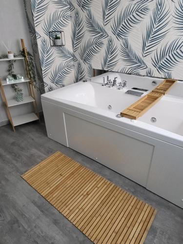 La salle de bains est pourvue d'une baignoire et de papier peint noir et blanc. dans l'établissement Bel appartement avec Balnéo, à Sainte-Marie-aux-Mines