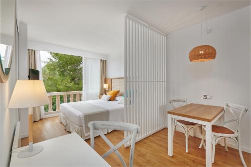 a bedroom with a bed and a desk and a table at Hotel Apartamentos Cala Santanyi in Cala Santanyi