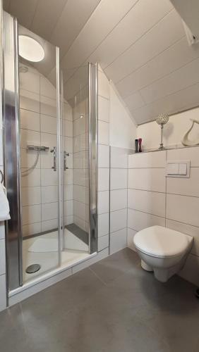 a white bathroom with a shower and a toilet at Hotel Schneiderhof in Braunlage