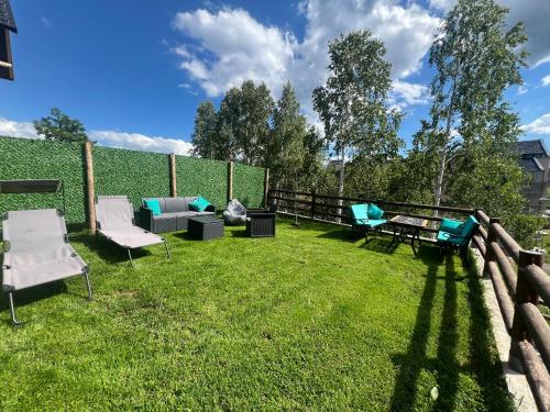 a patio with chairs and a table on a grass field at LUX PINE house in Zlatibor