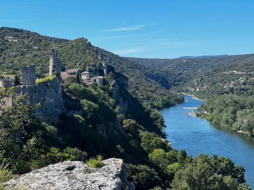 a castle on a cliff next to a river at Le clos des songes. in Saint-Christol-de-Rodières