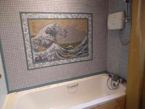 a bath tub in a bathroom with a painting of a wave at Red brick Victorian house next to Croke Park Stadium in Dublin