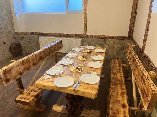 a long wooden table with plates and glasses on it at Къща за гости Оскови in Velingrad