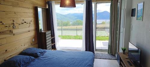une chambre avec un lit et une grande fenêtre dans l'établissement Entre Lac et Montagne - Piscine & Tennis, à Prunières