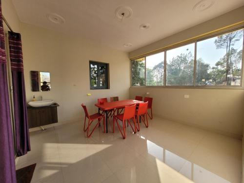a dining room with a red table and red chairs at 11 Gaon Homestay Lansdowne in Lansdowne