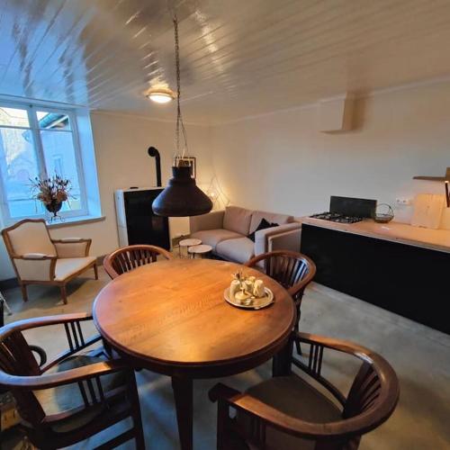 un salon avec une table et des chaises en bois dans l'établissement Frans dorpshuisje Maison Gerard, à Bussières-lès-Belmont