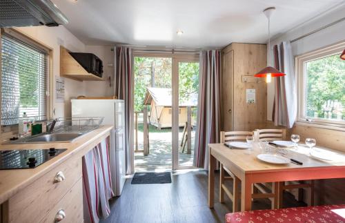 une cuisine avec une table en bois et une salle à manger dans l'établissement Huttopia Millau, à Millau