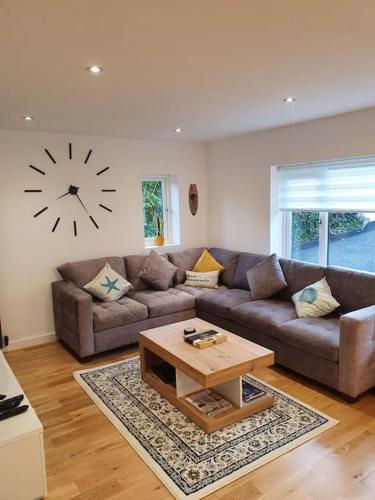 a living room with a couch and a clock on the wall at Clydfan No 1 Trearddur Road in Trearddur
