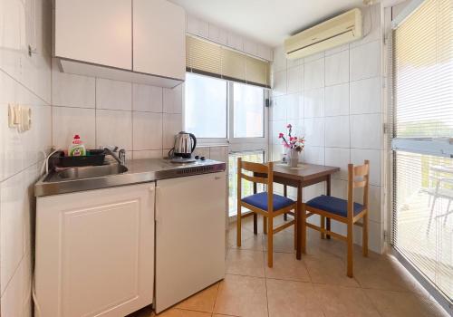 uma cozinha com um lavatório e uma mesa com cadeiras em Apartmani Danica em Orebić