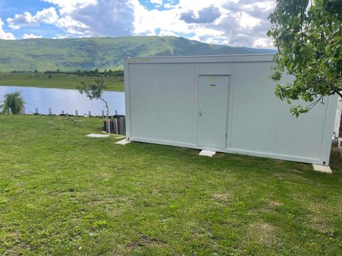 a large white building in the grass next to a body of water at Camp Tommy in Jaklići