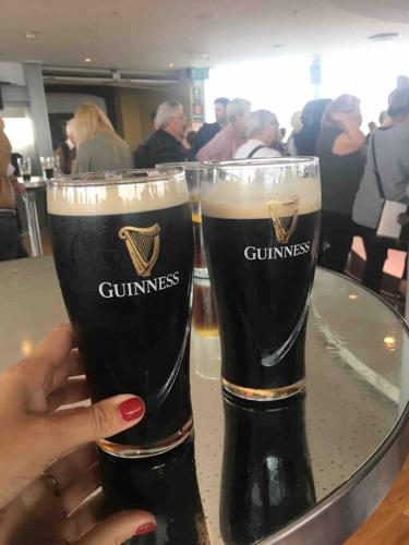 a woman holding two glasses of beer on a table at Clydfan No 1 Trearddur Road in Trearddur