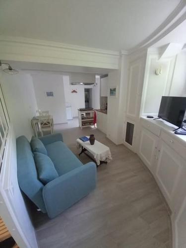 a living room with a blue couch and a table at Beau studio dans un cadre exceptionnel de verdure in Maisons-Laffitte