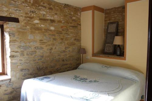 1 dormitorio con cama y pared de piedra en Casale Regnano, en Lama