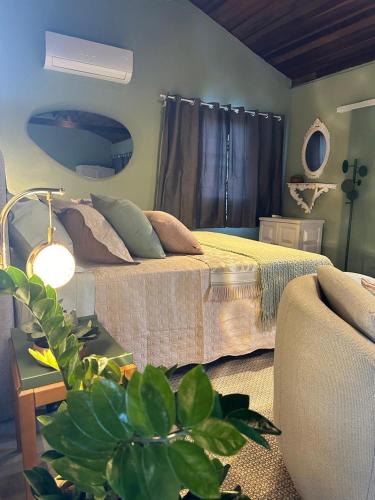 a bedroom with a bed and a couch and a plant at La Casa de Due in Serra Negra