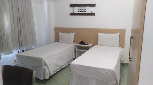 een kamer met twee bedden en een telefoon op een tafel bij Hotel Champs Dumont in Macaé