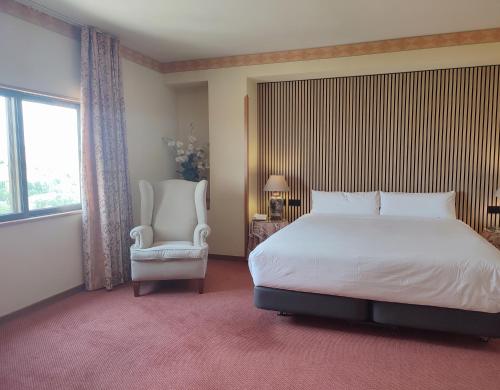a bedroom with a bed and a chair and a window at Hotel Sercotel Cuatro Postes in Avila