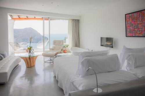 a white room with a bed and a view of the ocean at Hacienda Na Xamena, Ibiza in Na Xamena