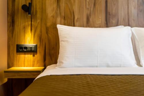 a bed with a white pillow and a wooden wall at The Dorians in Athens