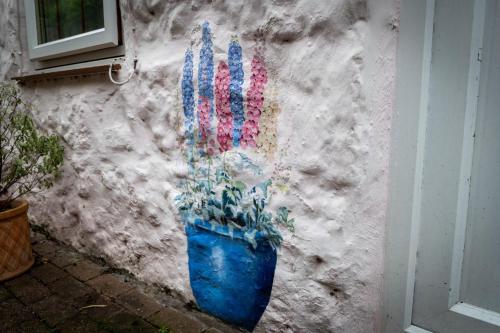 a painting of a plant in a blue pot on a wall at Ty Hydref in Beaumaris